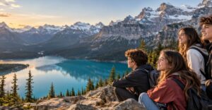 Grupo de jóvenes sentados en las rocas contemplando un lago turquesa y las montañas nevadas de Canadá al atardecer Grupo de jóvenes sentados en las rocas contemplando un lago turquesa y las montañas nevadas de Canadá al atardecer